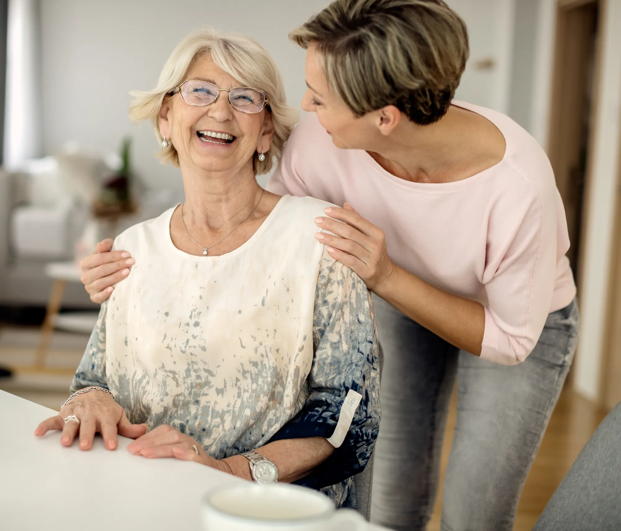 Uśmiechnięta seniorka i kobieta, która obejmuje ją za ramiona